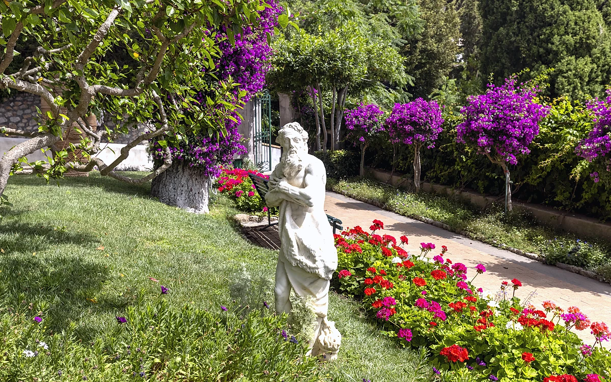 Capri Adası Augustus Bahçeleri'nde begonviller ve antik heykellerle süslü yürüyüş yolu.