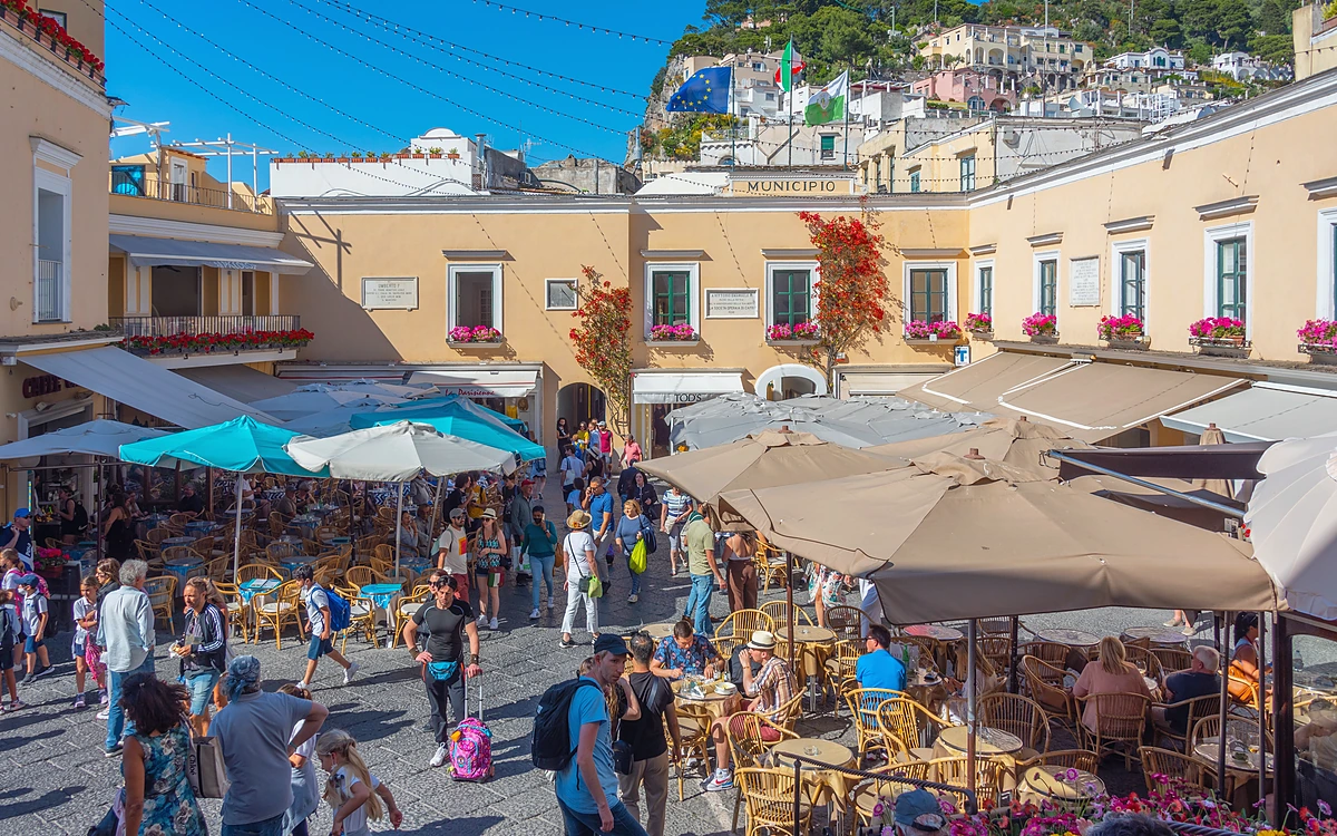 Capri Adası Piazzetta meydanında yer alan kafeler, Municipio binası ve kalabalık turist grupları.