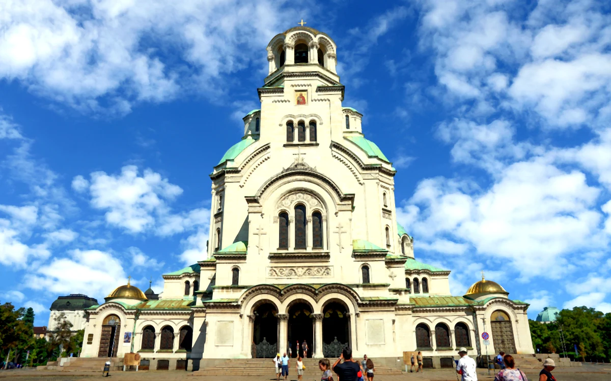 Sofya'daki Aziz Aleksandr Nevski Katedrali'nin tam karşıdan görünümü; beyaz cephe, yeşil ve altın kubbeler, mavi bulutlu gökyüzü.