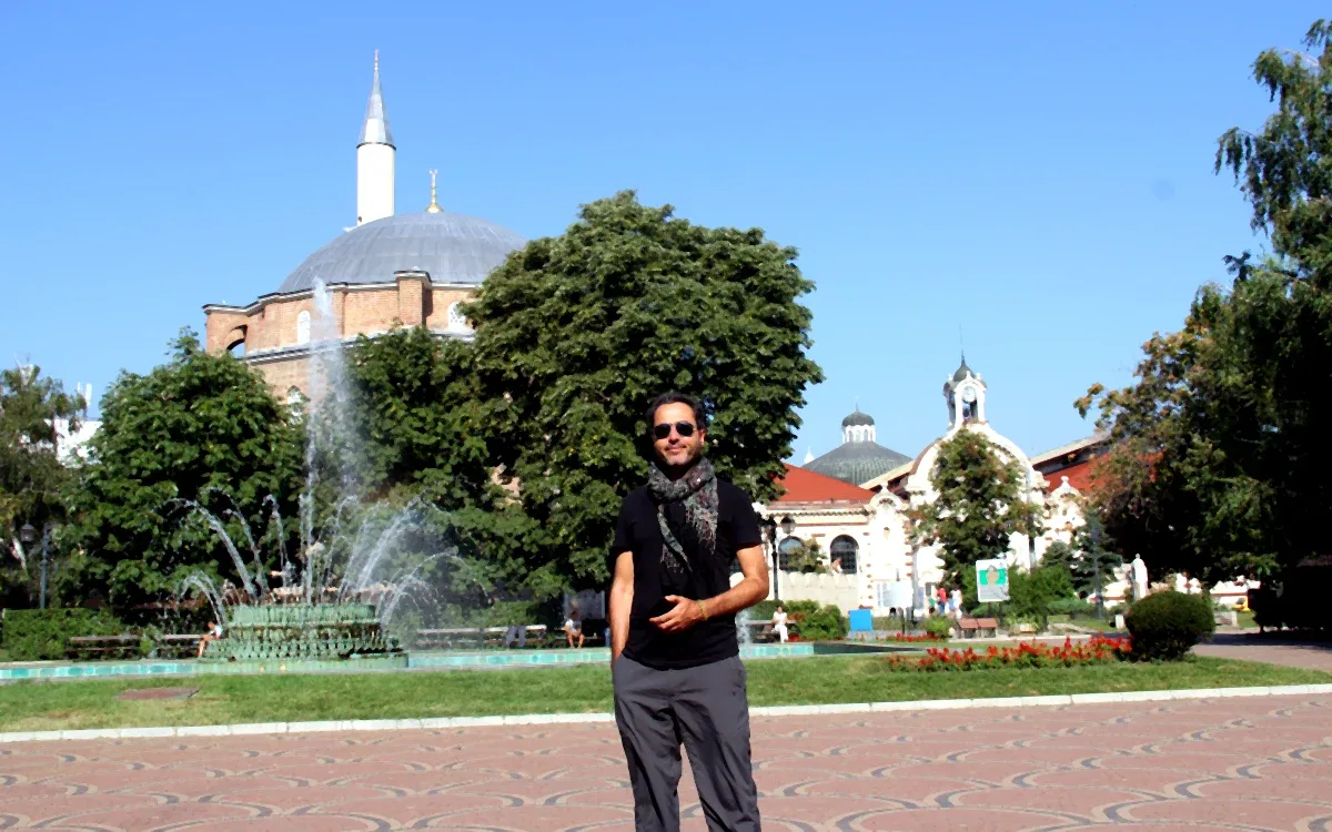 Sofya Banyabaşı Camii önünde çekilmiş bir portre fotoğrafı; arka planda tarihi Osmanlı mimarisi ve minare.