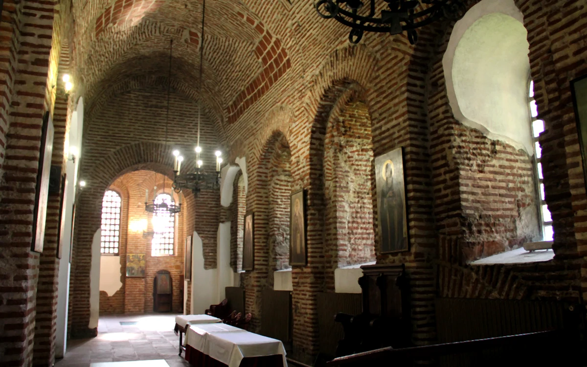 Aziz Sofia Kilisesi'nin iç mekanı; tuğla duvarlar, ikonalar ve asılı avizeler.