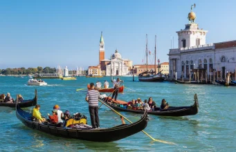 Venedik kanallarında gondol turu yapan insanlar ve tarihi binalar