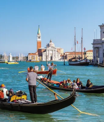 Venedik kanallarında gondol turu yapan insanlar ve tarihi binalar