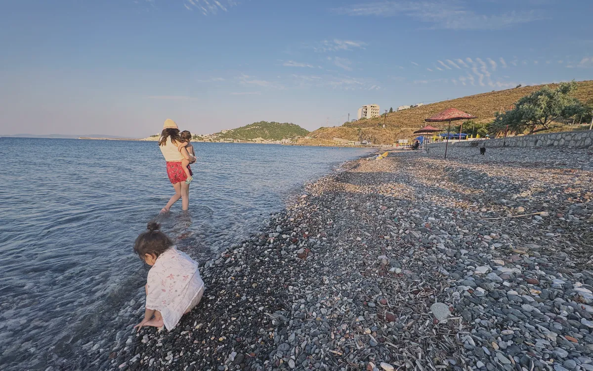 Karaburun'da çakıllı kıyıda denize giren kadın ve çocuklar