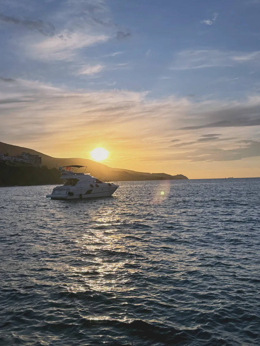 Karaburun kıyısında gün batımı ve denizde beyaz motor yat