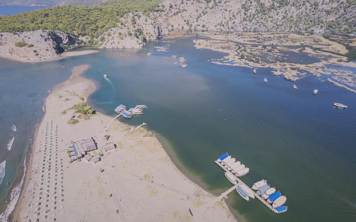 Köyceğiz'de Iztuzu Plajı'nın ve Dalyan Nehri'nin kuşbakışı görünümü, tekneler ve şezlonglar.