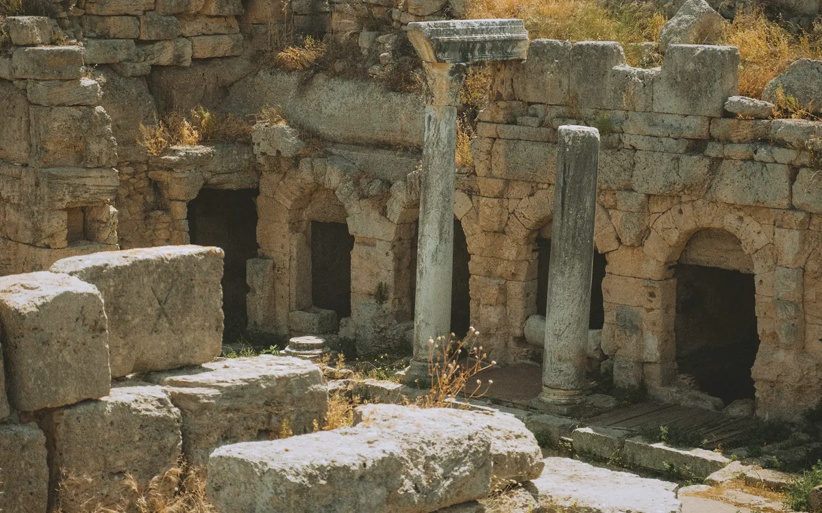 Antik bir yapının kalıntıları, yıkık taş duvarlar, ayakta kalmış sütunlar ve kemerli girişler.